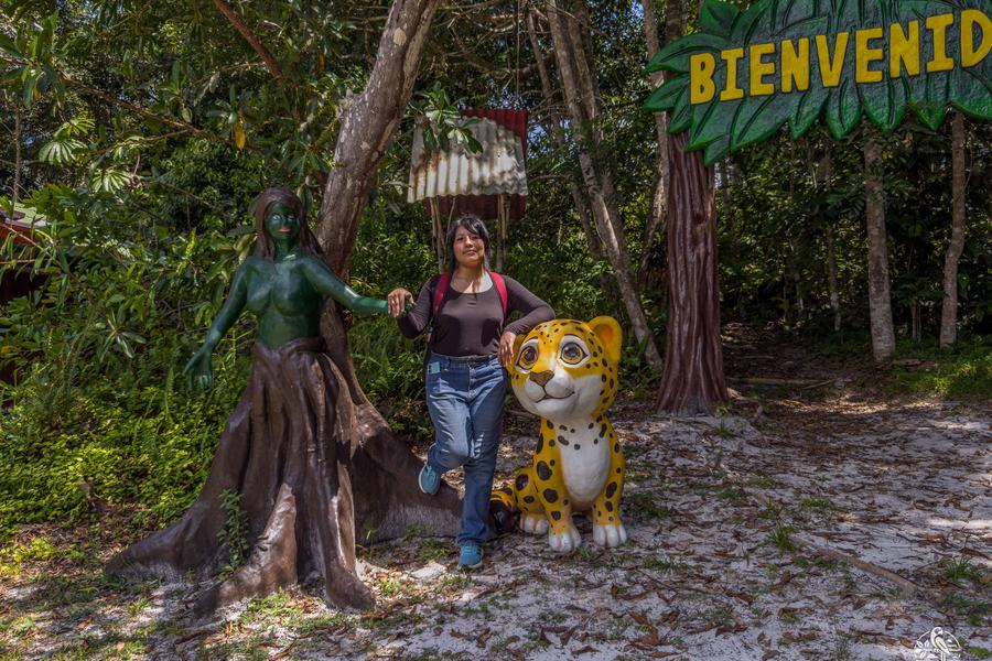 Visitante junto a las figuras de bienvenida del Centro de Rescate Amazónico